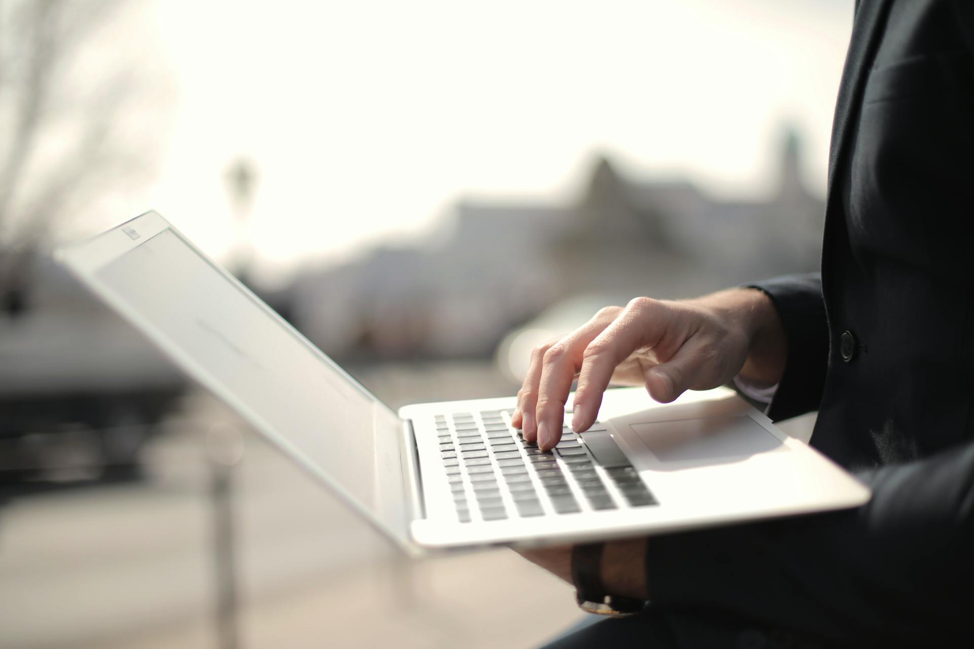 A business professional typing on a laptop in an outdoor setting, symbolizing remote work.