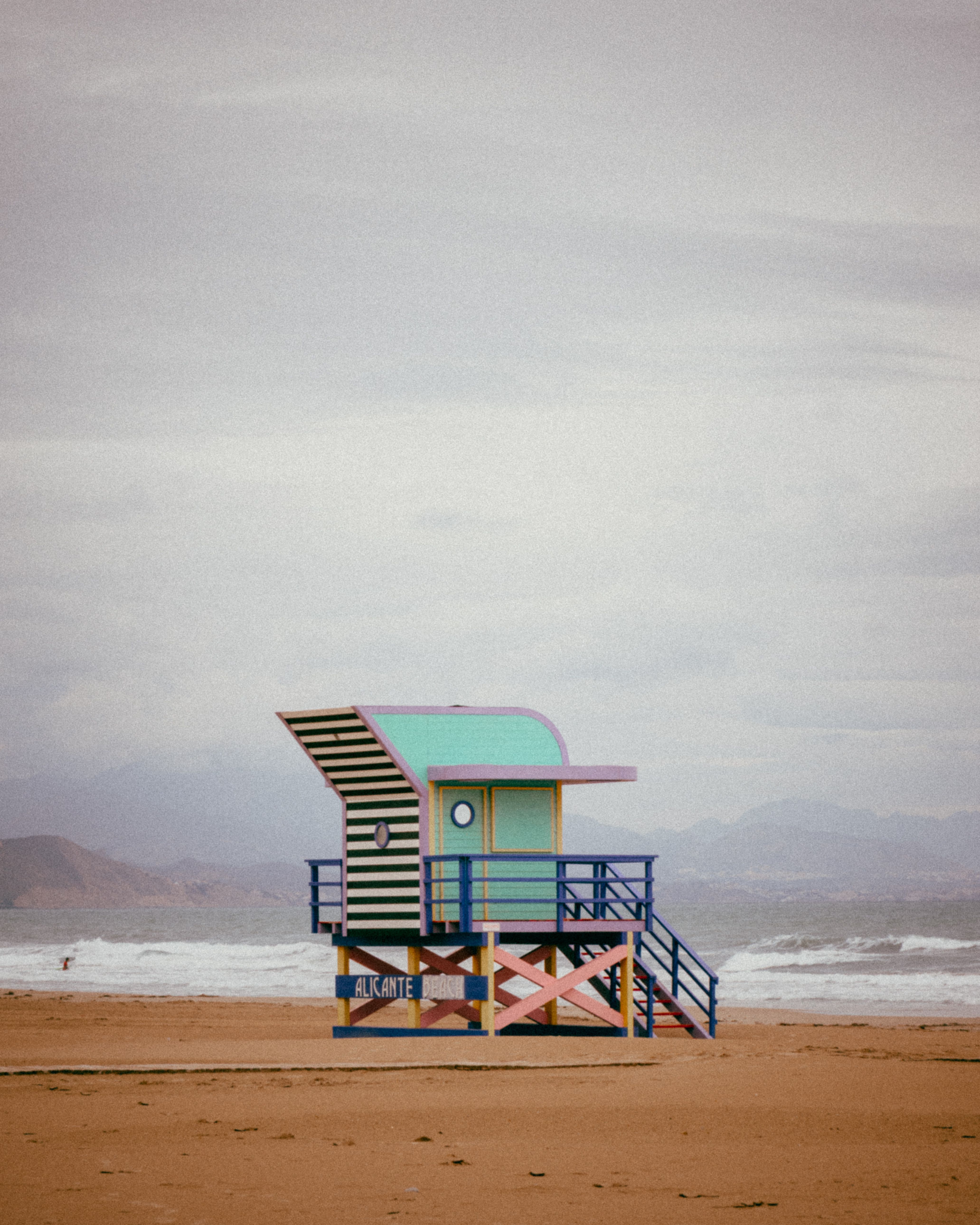 Vibrant lifeguard tower stands against a serene beach backdrop, creating a striking coastal scene.