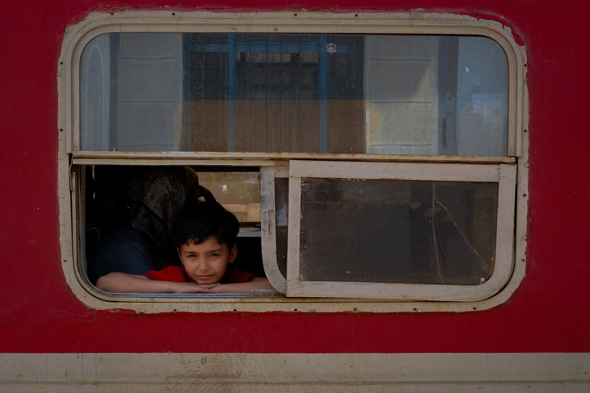 A young boy looks out the window of a train in Egypt, evoking the Cairo to Alexandria rail journey along the Nile Delta