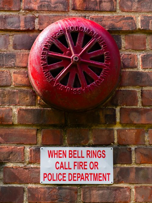 Free A vintage fire alarm bell with a sign on a brick wall in New York. Stock Photo