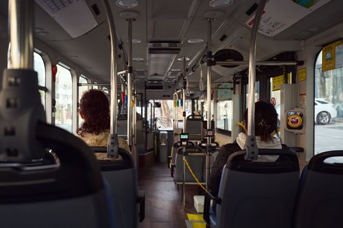 Free View of a public bus interior with seated passengers and visible city streets outside. Stock Photo