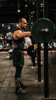 Male weightlifter exercises in a gym lifting heavyweights, showcasing strength and endurance.