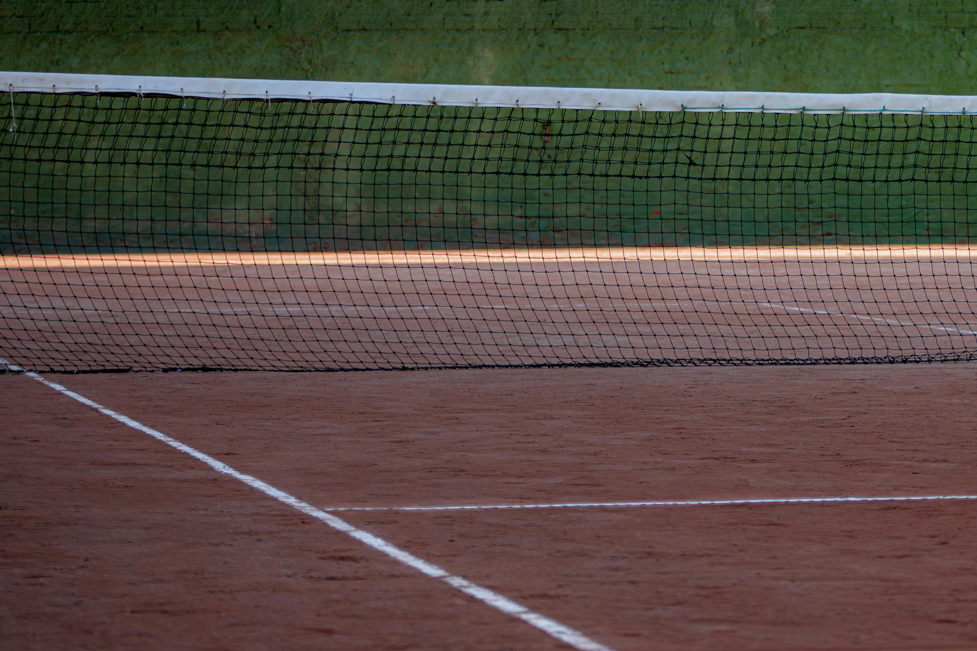 An empty clay tennis court in daylight