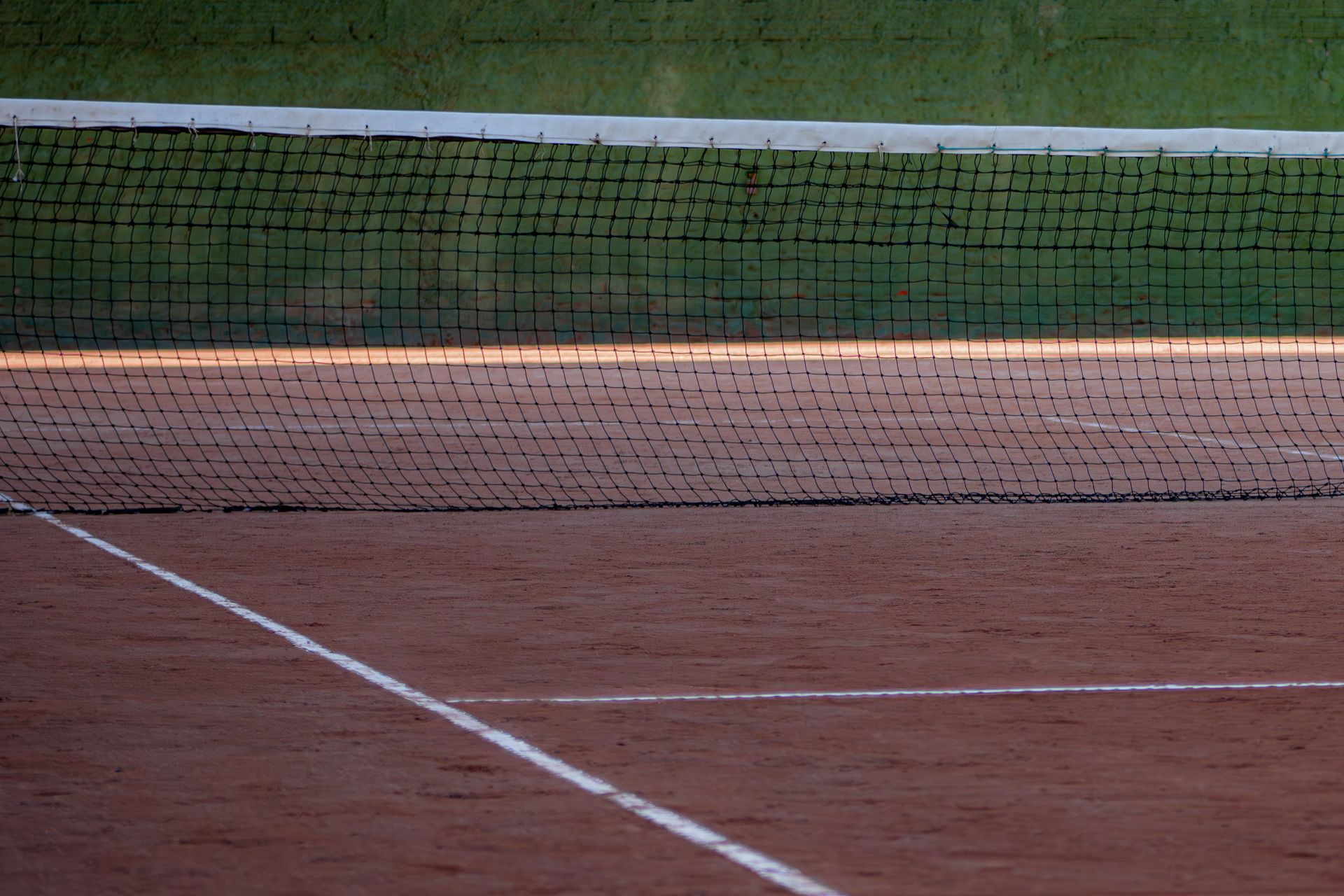 An empty clay tennis court in daylight