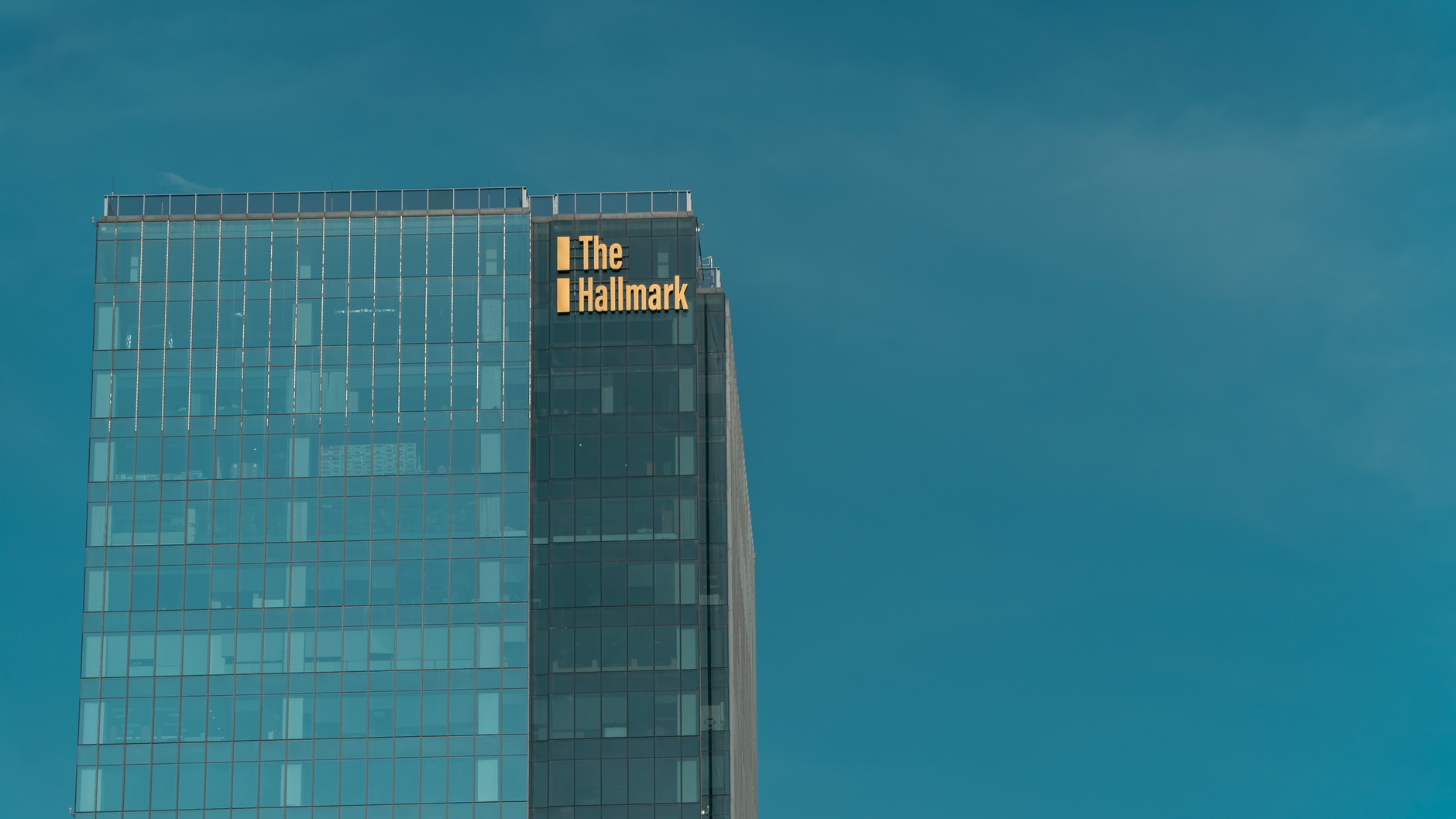 A view of a tall building with The Hallmark signage against a clear sky.