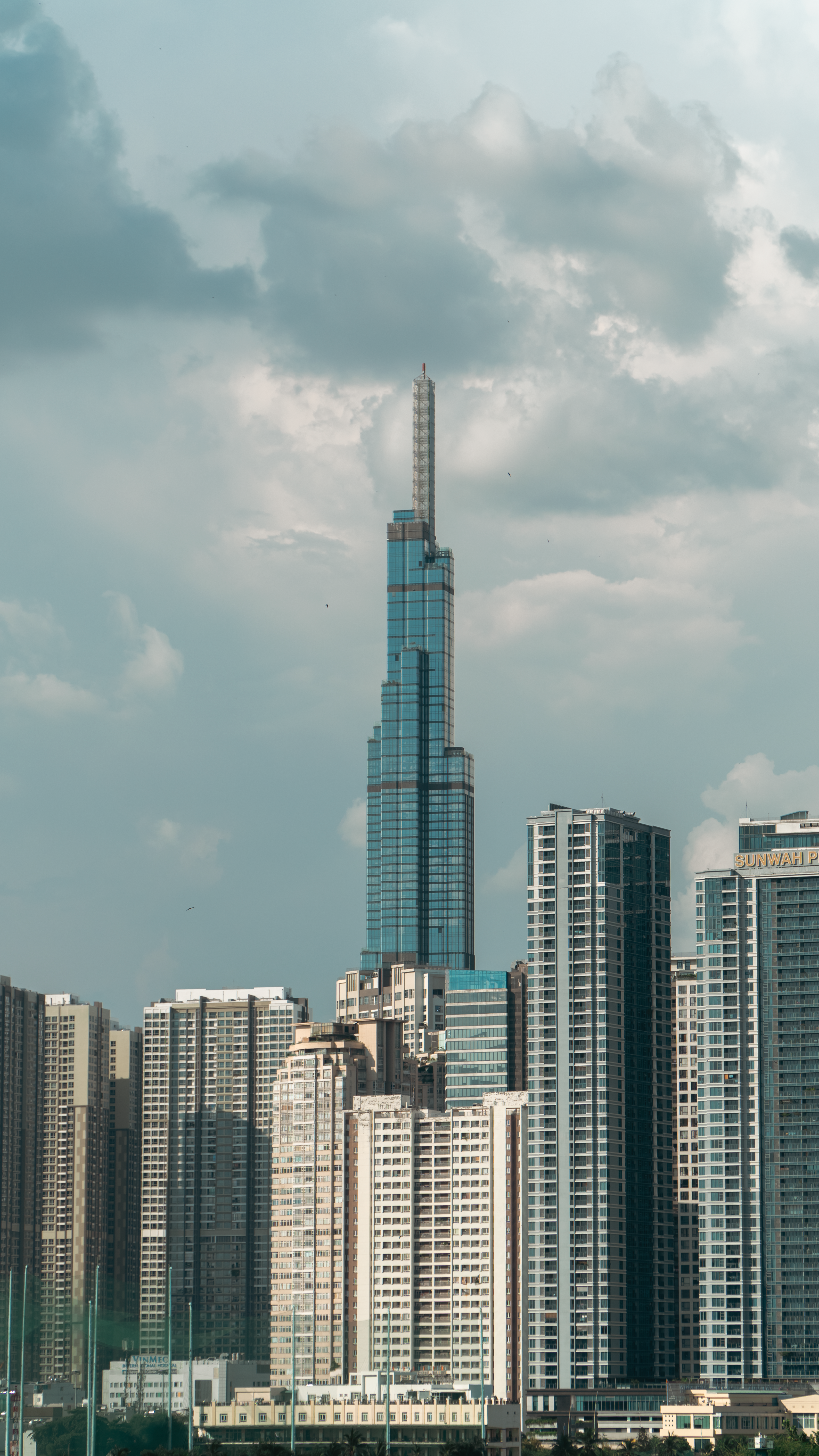 High-rise cityscape featuring a prominent skyscraper under a cloudy sky.