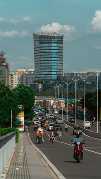 Vibrant urban scene featuring a busy road and modern skyscraper under a blue sky.