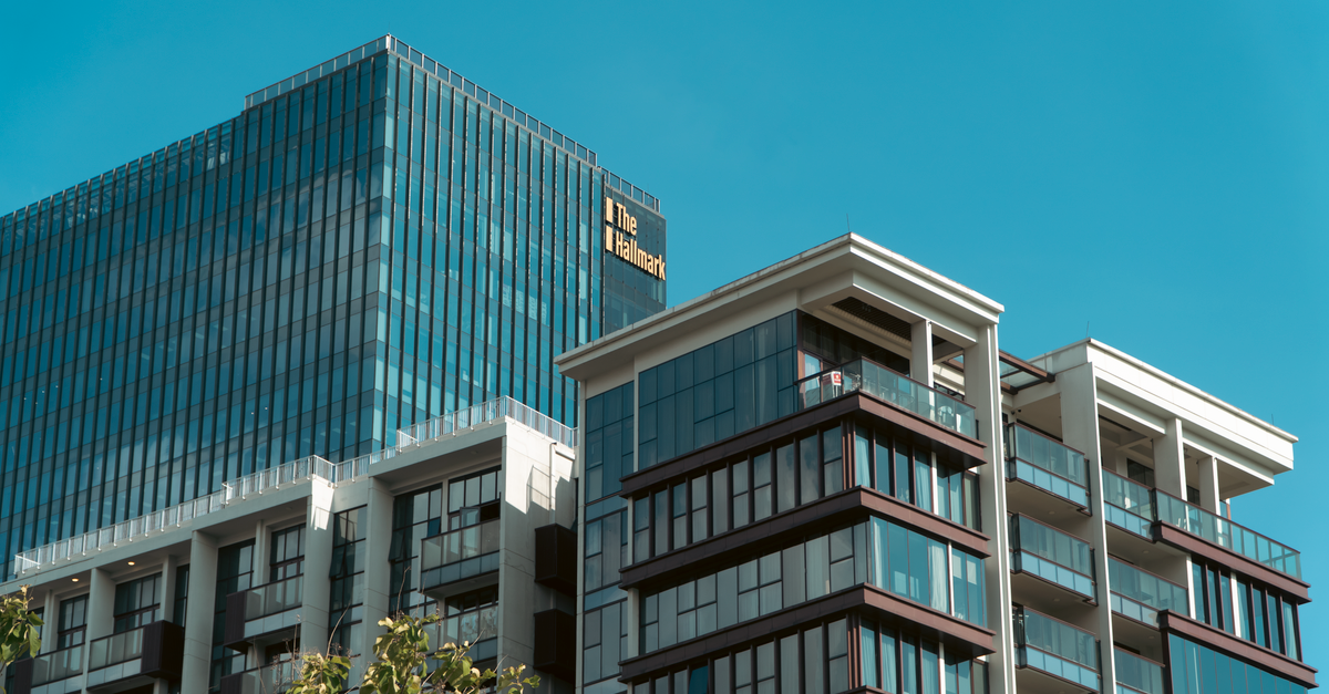 Contemporary glass and steel buildings under a bright blue sky, showcasing urban architecture.