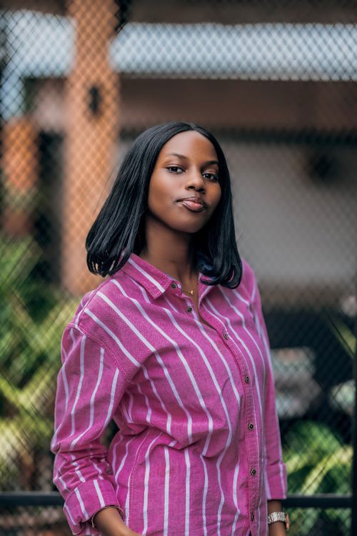 Free Confident young woman in a stylish pink striped shirt posing outdoors. Stock Photo