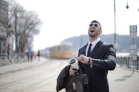 戴着墨镜的商人在户外拿着咖啡杯开怀大笑，充满了活力与感染力