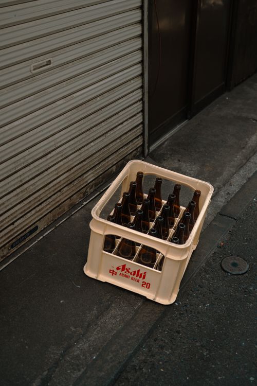 Free A crate of empty beer bottles on a Tokyo street, highlighting urban life. Stock Photo