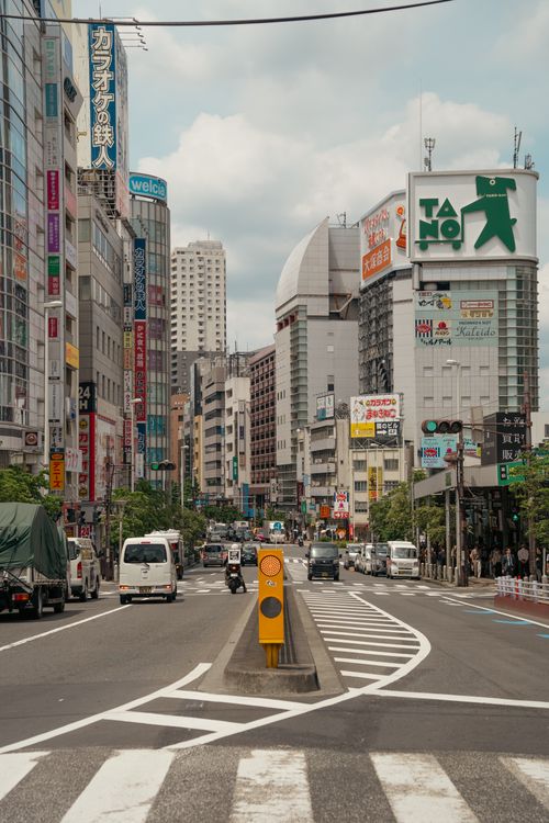 Free Explore a vibrant street in Tokyo filled with city life and modern architecture under a cloudy sky. Stock Photo