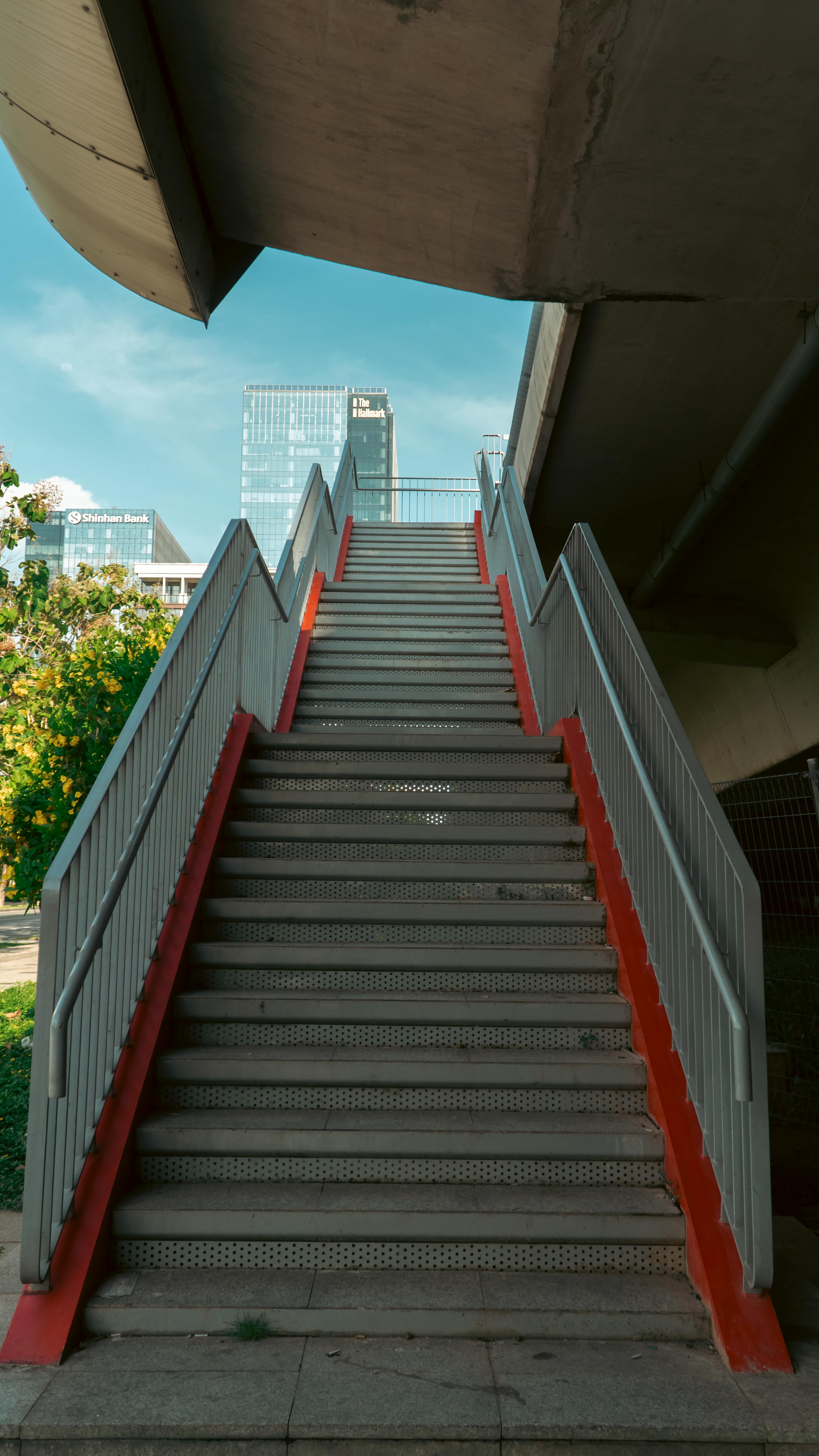 Empty staircase in modern city scene leading to skyscrapers under clear blue sky.