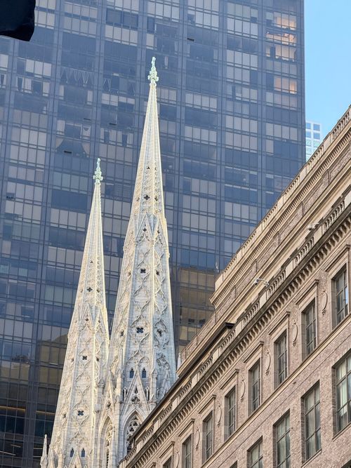 Free St. Patrick's Cathedral spires against a modern building backdrop in New York City. Stock Photo