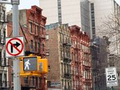 Historic New York City street with red brick brownstones and traffic signs.