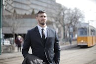 一位严肃的商人穿着西装，站在户外电车轨道附近