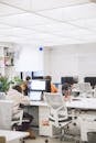 People Sitting on White Chairs in Front of Computer Monitor