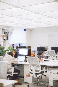Bright modern office interior with employees working on computers. Ideal for business and productivity concepts.