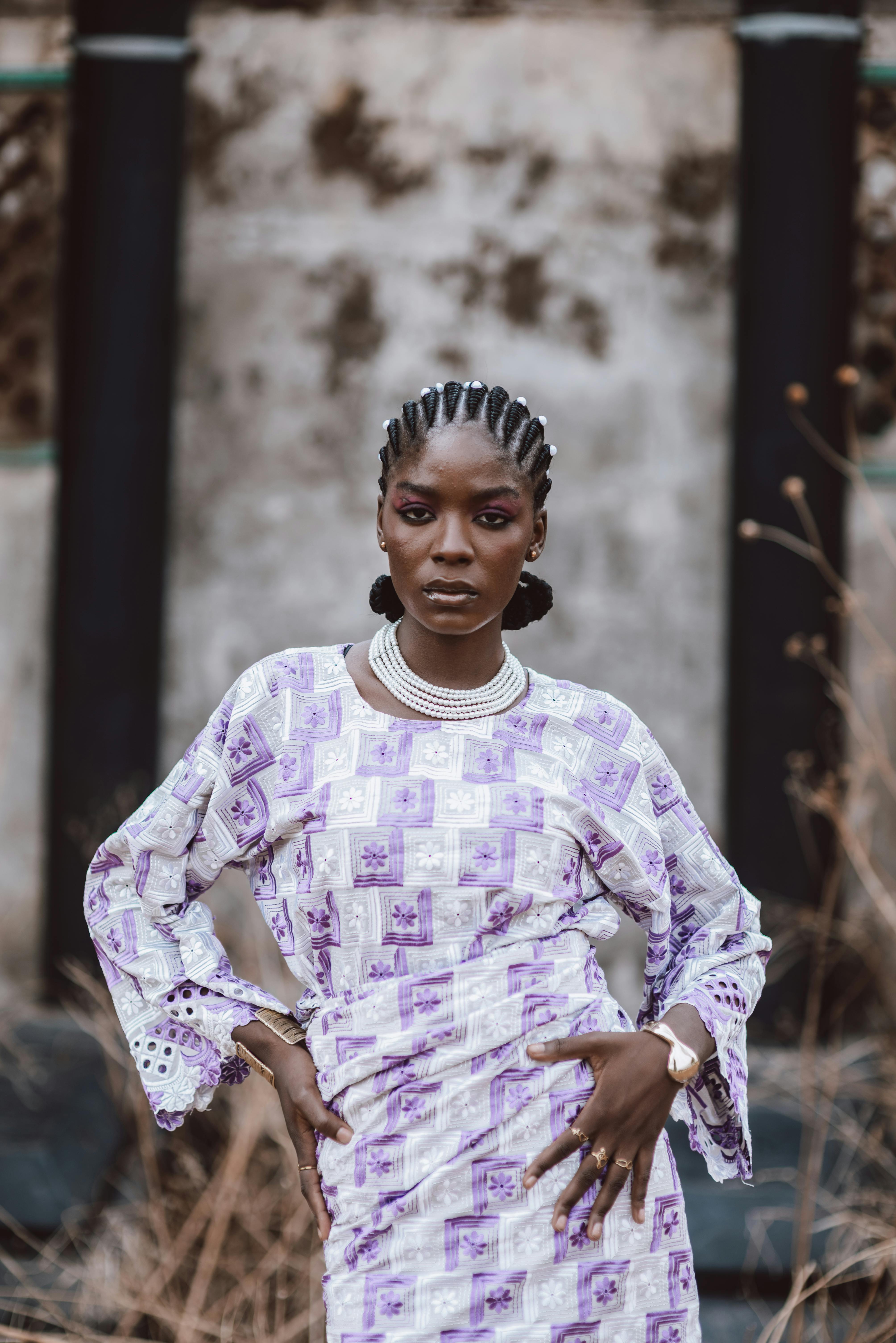 Confident woman in patterned African dress poses outdoors. Strong composition and vibrant style.