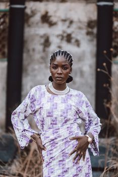 Confident woman in patterned African dress poses outdoors. Strong composition and vibrant style.