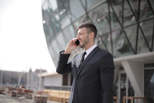 Man in Black Suit Jacket While Using Smartphone