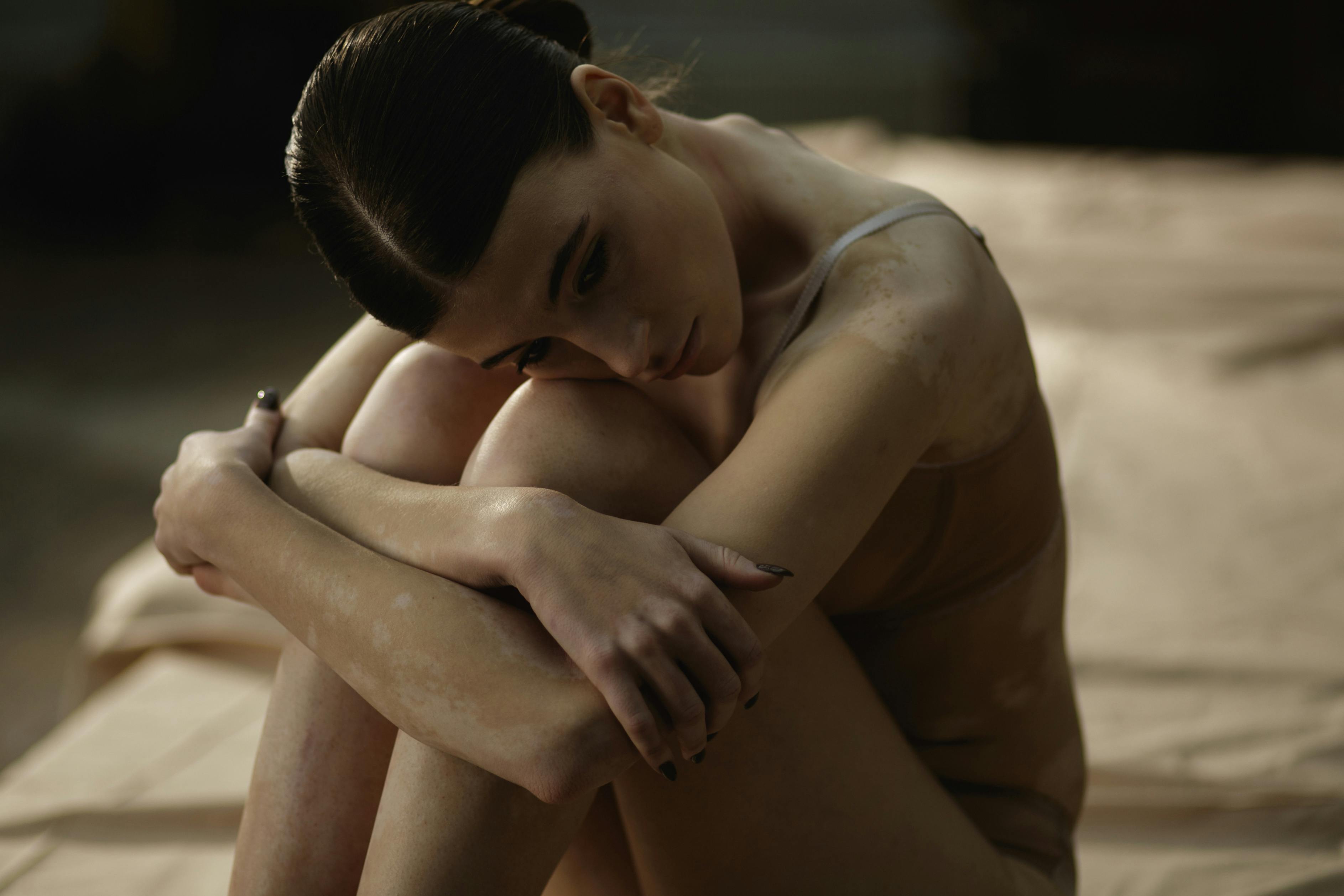 topless woman sitting on brown blanket