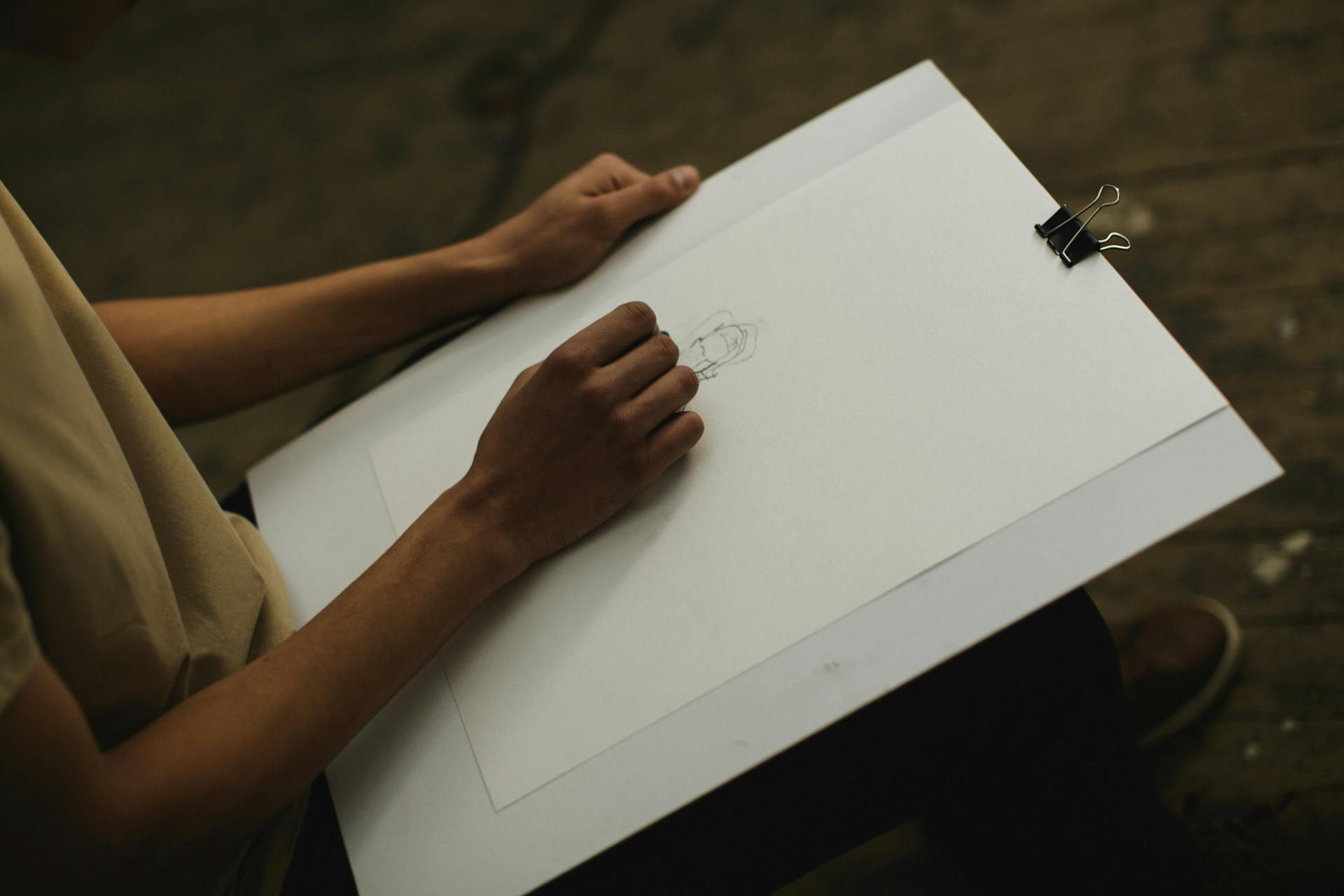 Artist focused on sketching a portrait in dim indoor lighting, creating art.