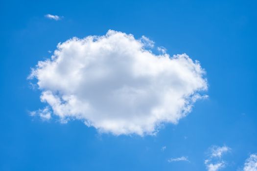 A single fluffy white cloud against a vibrant blue sky on a clear summer day.