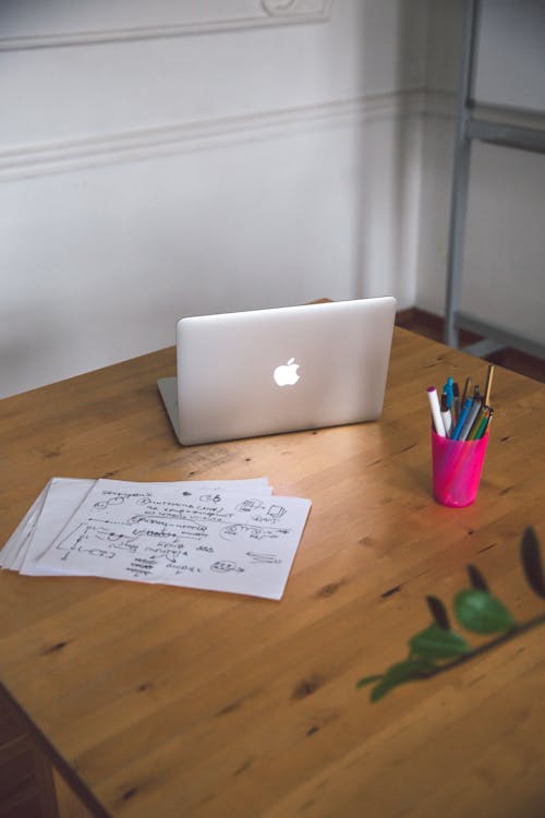 White Printer Paper on Brown Wooden Table Next To Laptop · Free Stock Photo