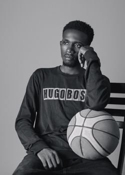 Monochrome image of a thoughtful man with a basketball in a casual setting.
