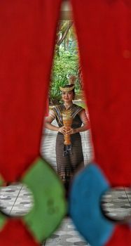 Indonesian dancer in traditional attire framed by vibrant red and green art pieces. - Fotografer Sidoarjo