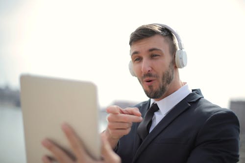 Man in Black Suit Jacket While Wearing White Headphones