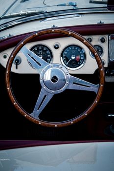 Close-up of a classic car's dashboard and steering wheel showcasing vintage design and luxury.
