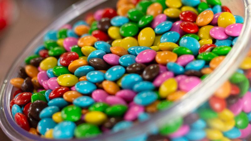 A glass bowl filled with colorful candy-coated chocolates, perfect for a festive party setting.