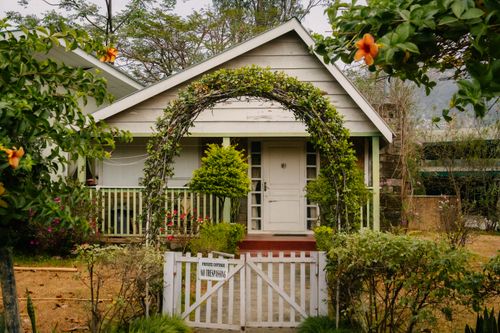 Free A quaint cottage with lush greenery and a welcoming gate in a garden setting. Stock Photo