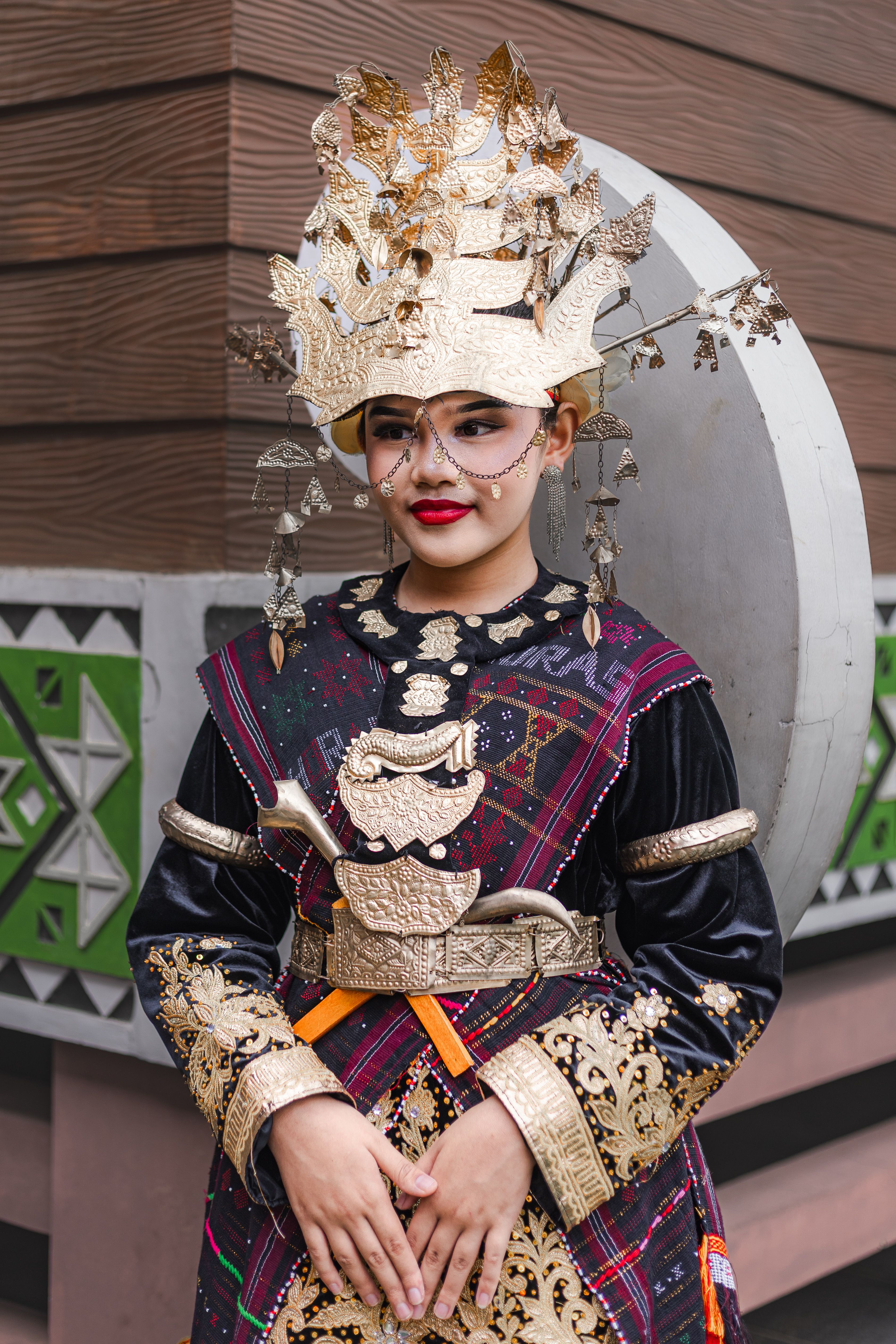 Portrait of a woman in traditional Indonesian costume with elaborate headdress.