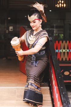A woman in traditional attire performs a cultural dance while playing a drum indoors. - Fotografer Sidoarjo