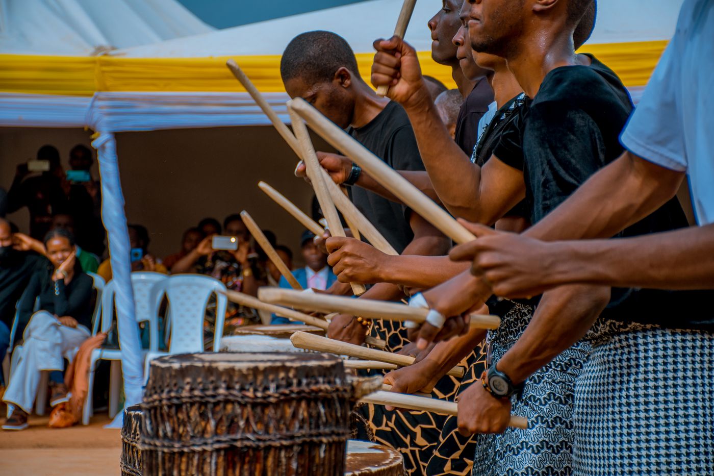 Group of African drummers performing at an outdoor cultural event with onlookers
