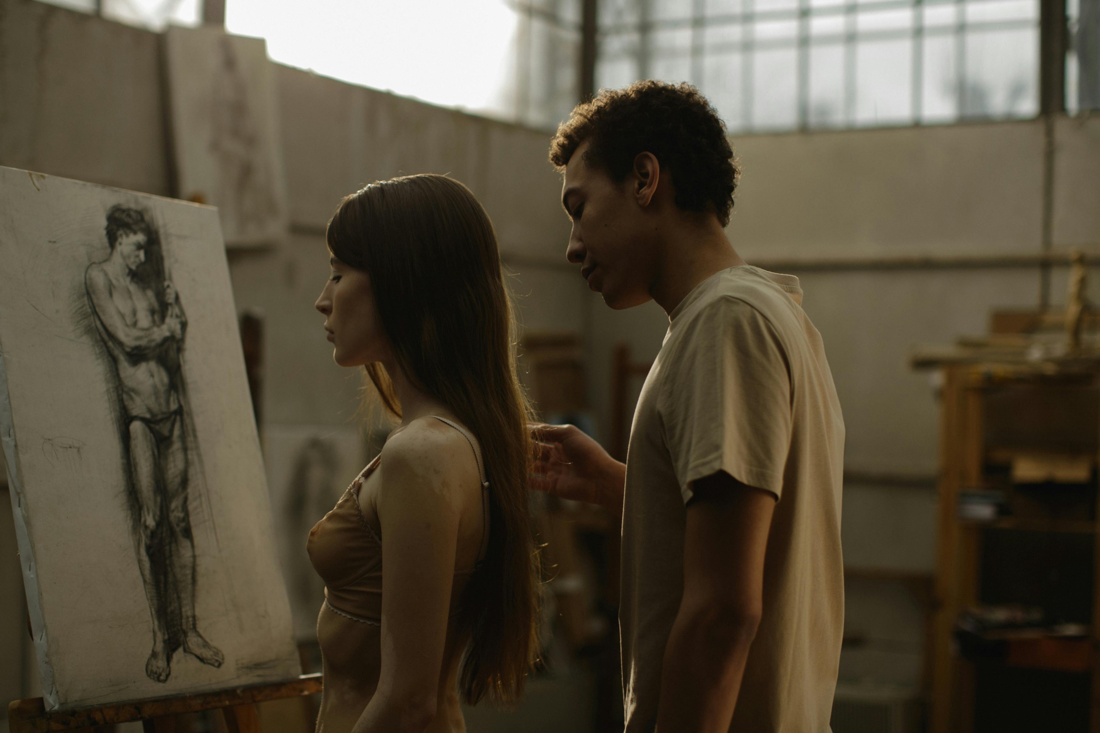 man in brown t shirt standing beside woman in brown brassiere