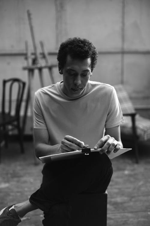 Photo of a Man Holding a Charcoal and White Cardboard