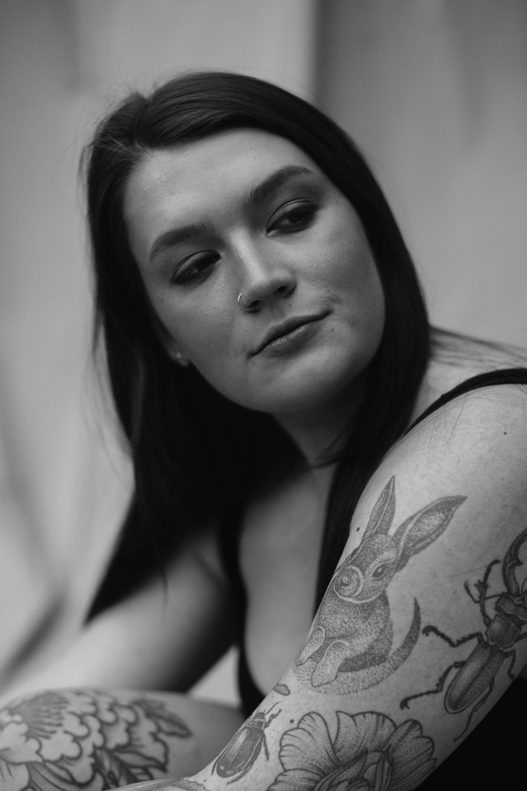 Close portrait of a tattooed woman with dark hair against a dark studio background