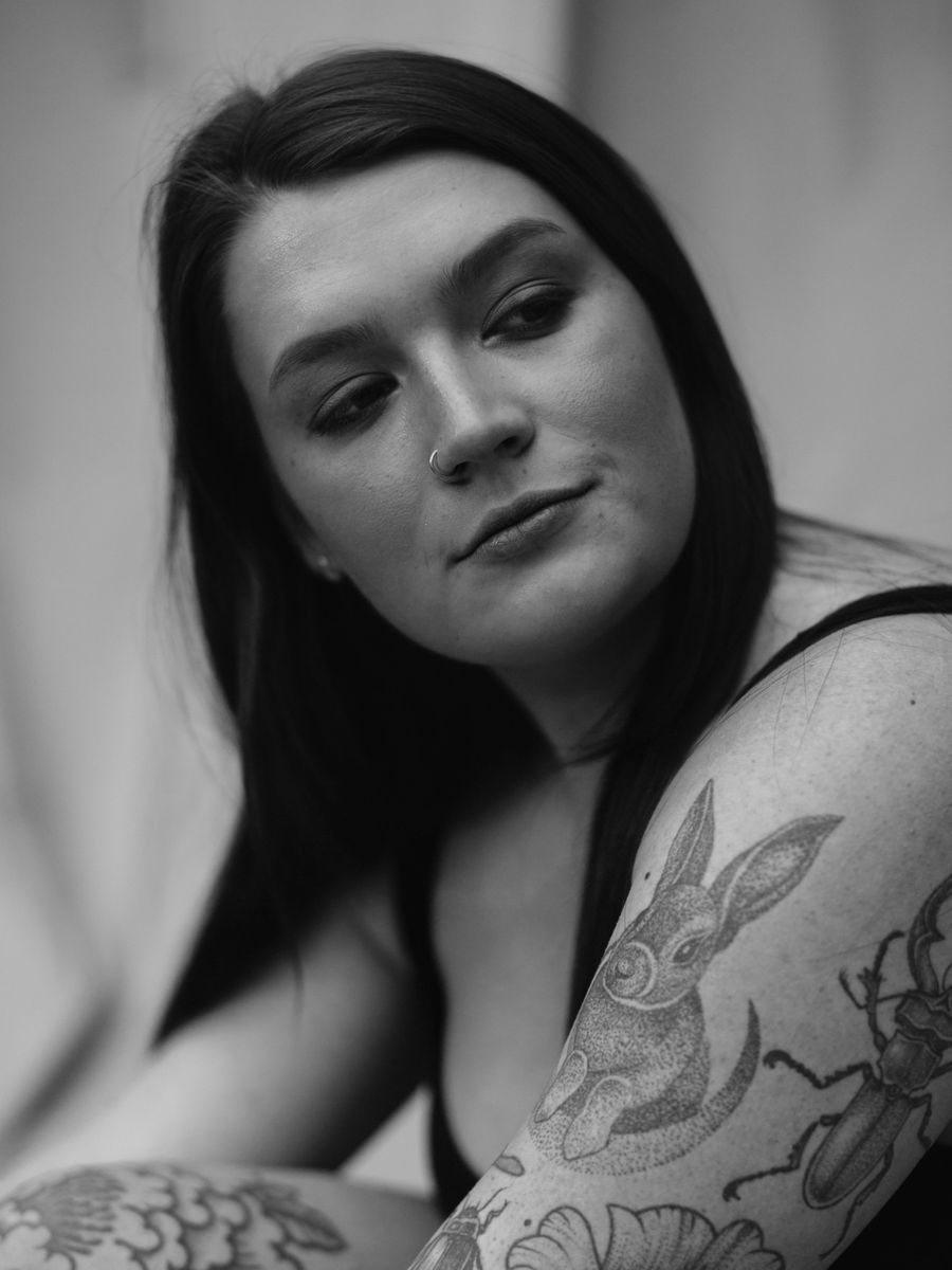 A black-and-grey portrait study of a tattooed woman.