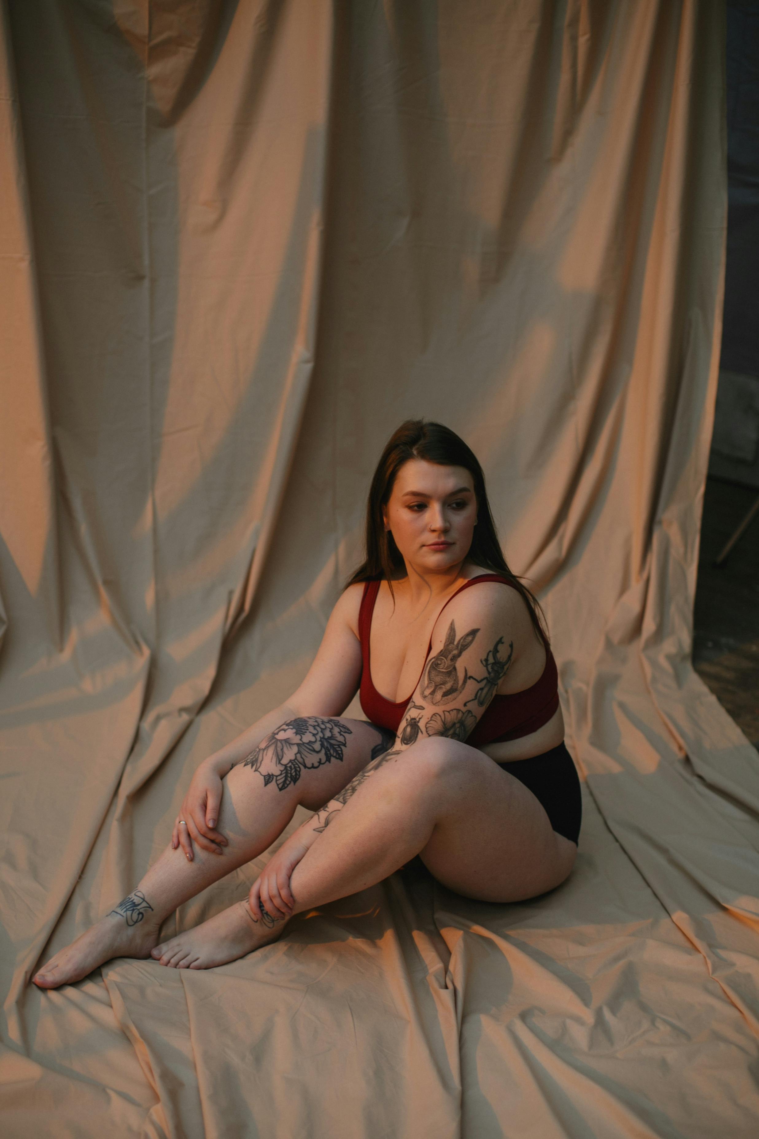 woman in red brassiere sitting on brown blanket