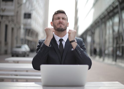 Free Man in Black Suit Sitting on Chair Beside Buildings Stock Photo