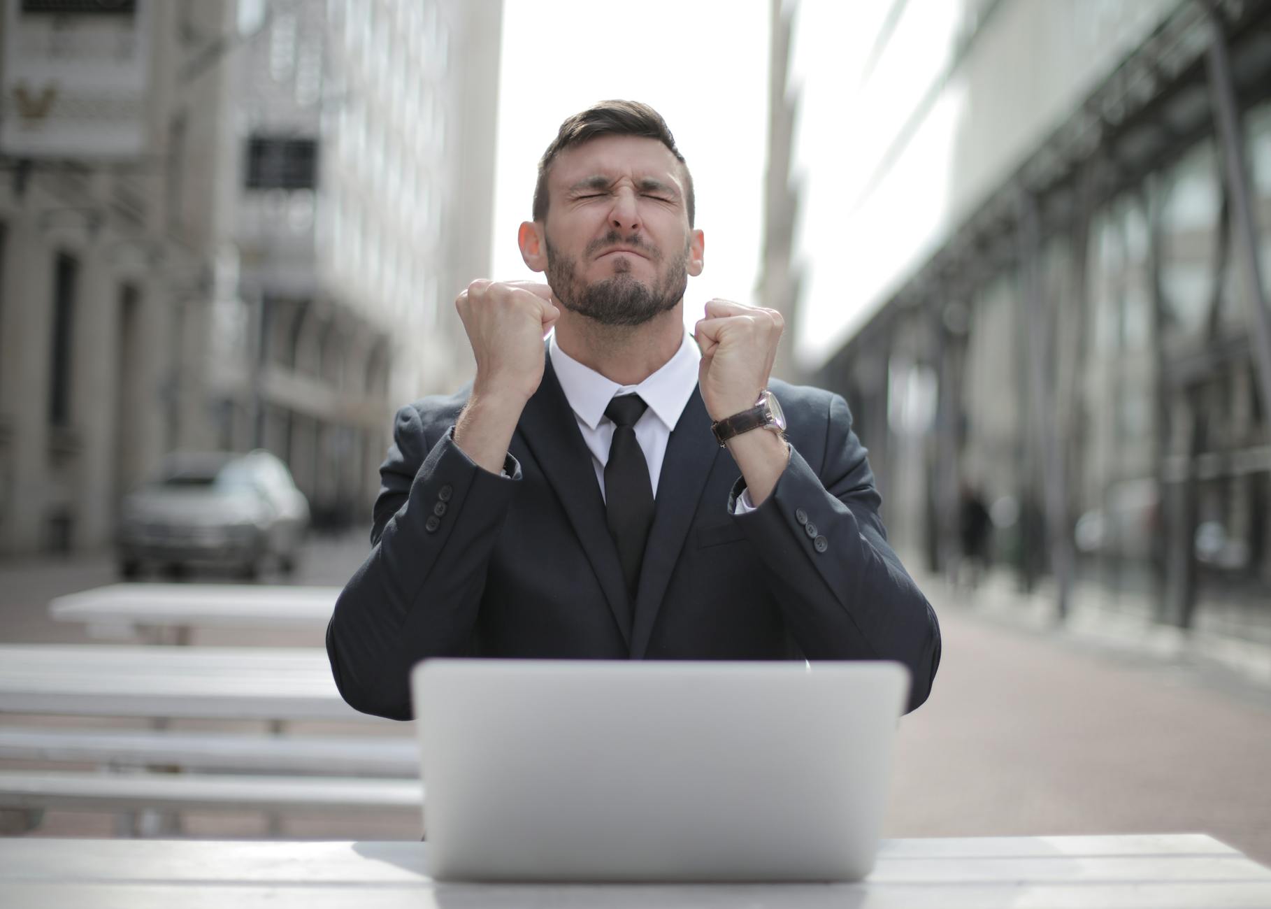 Man in Black Suit Sitting on Chair Beside Buildings