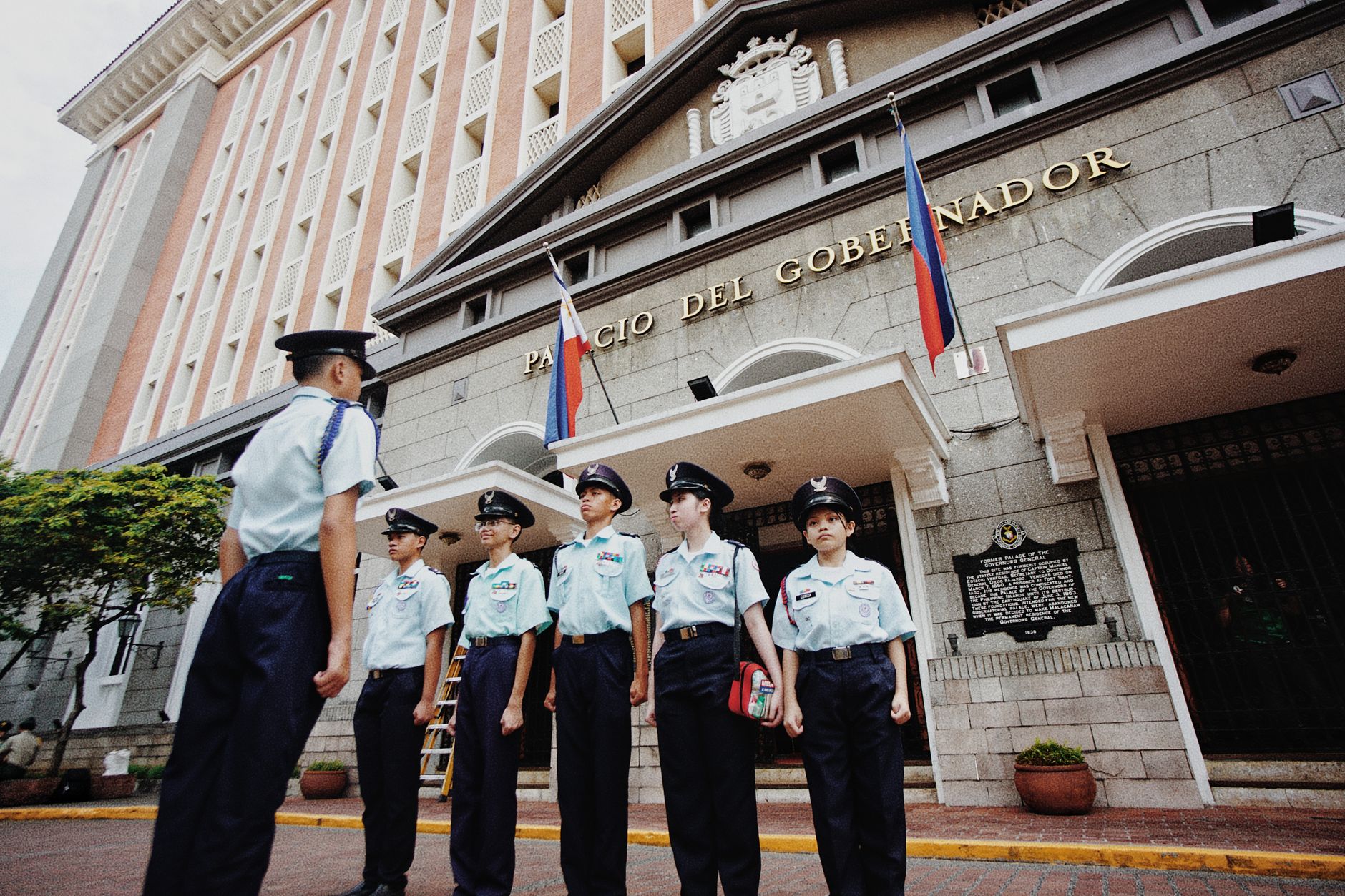 Philippine cockfighting arena with official license board, empty seats, and morning security inspection