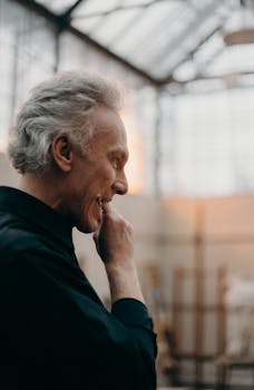 一位头发花白的老人，富有洞察力，侧身在艺术工作室中