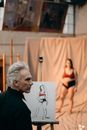 在工作室的艺术研讨会上，一位艺术家正专注于画一位女模特