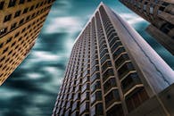 低角度镜头以引人注目的方式突出了旧金山现代摩天大楼在阴云密布的天空下的景象