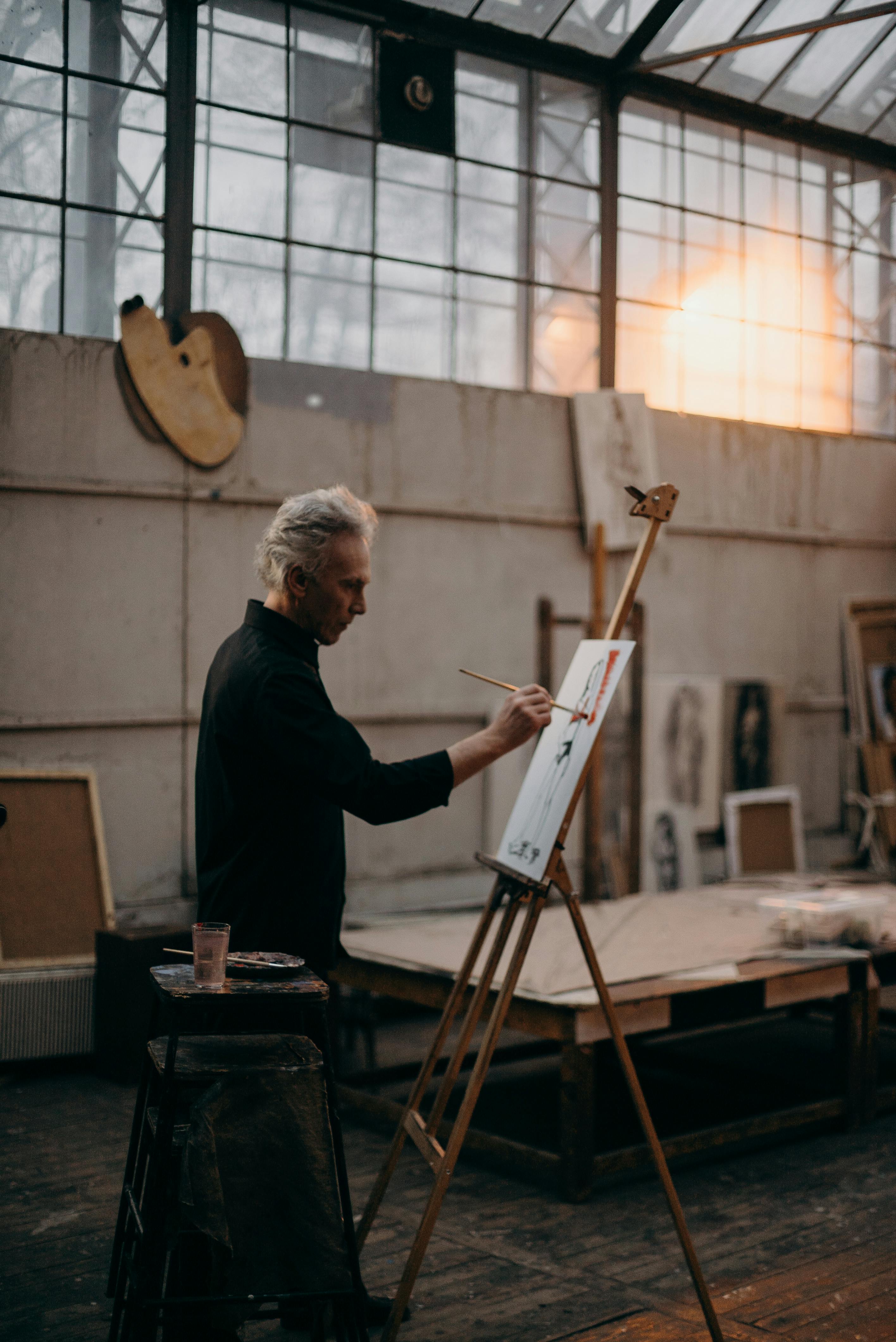 a serious man painting on a white cardboard
